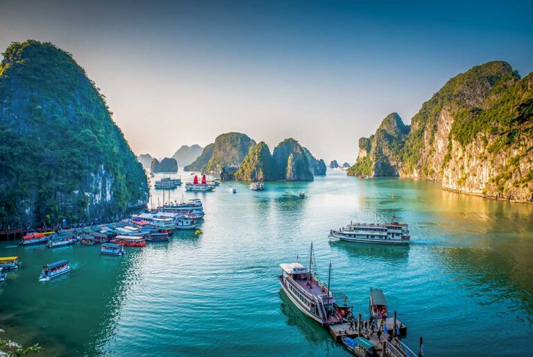 Cruise boats gliding through limestone islands in Halong Bay – a scenic highlight often included in Vietnam tours.