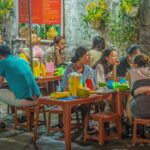 Ho Chi Minh City food tours enjoying local street food at busy evening eateries with small tables and authentic Vietnamese dishes