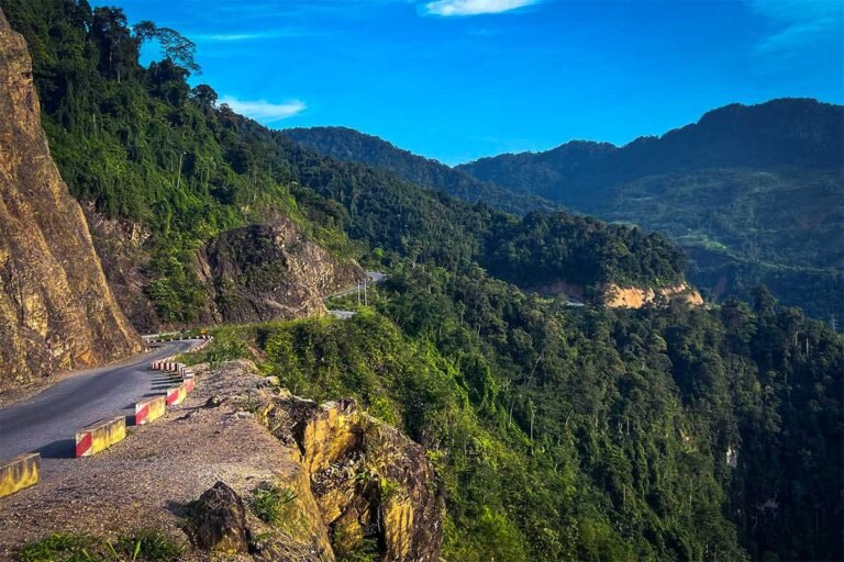 Scenic mountain road along the A Boong route in Ha Giang, a remote and quiet stretch of the Ha Giang Loop surrounded by forested valleys and steep cliffs