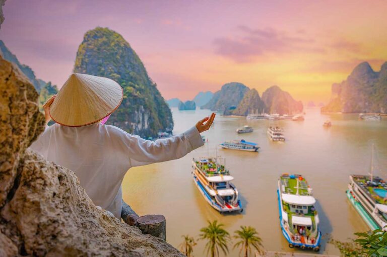 Best things to do in Vietnam, capturing a scenic viewpoint over Halong Bay with limestone karsts, traditional boats, and calm emerald water.
