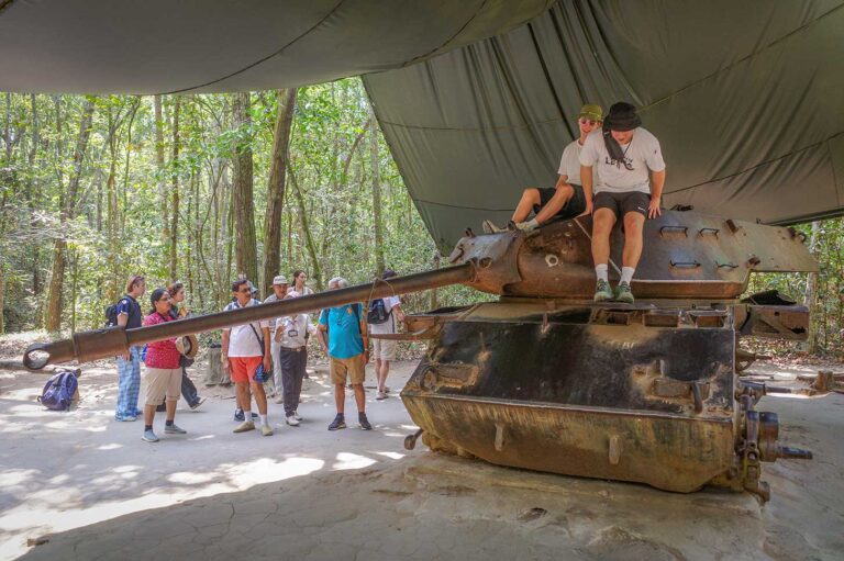 Best Vietnam War sights to visit in Vietnam, showing visitors exploring a preserved American tank at the Cu Chi Tunnels near Ho Chi Minh City.