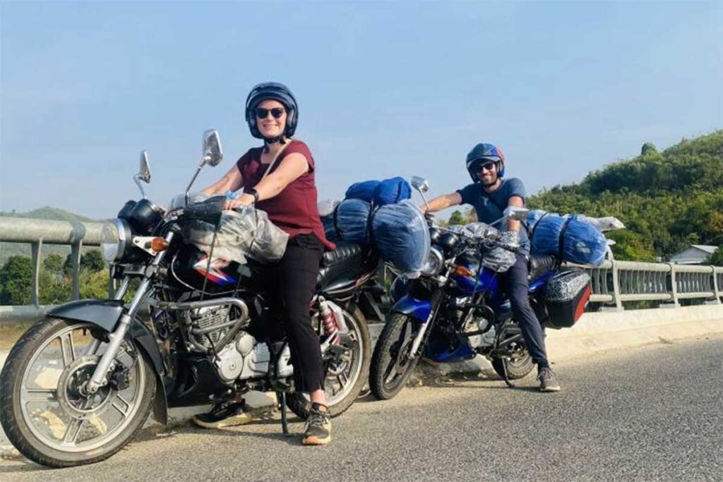 Travellers riding motorbikes on a Dalat to Nha Trang Easy Rider tour, stopping on a mountain road with views over forested hills