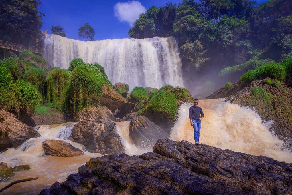 Traveler posing at Elephant Waterfall in Dalat with cascading water and misty surroundings