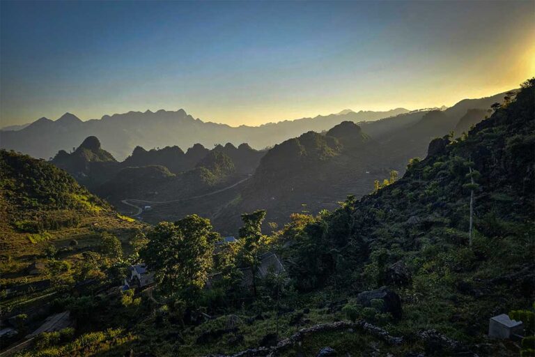 Sunset over the mountains near Ha Giang Aya Lodge, with layered karst peaks and quiet valleys along the Ha Giang Loop