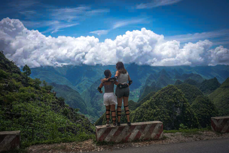 Ha Giang Loop Easy Rider motorbike tour with Local Vietnam, showing two guests standing together at a roadside viewpoint overlooking green valleys and mountain ridges