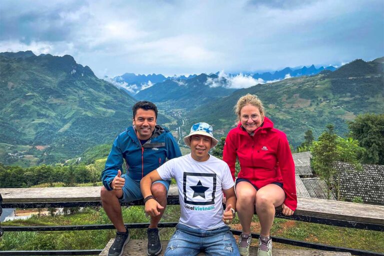 Local Vietnam guide with travelers during a Ha Giang Loop tour, enjoying panoramic mountain views along the route