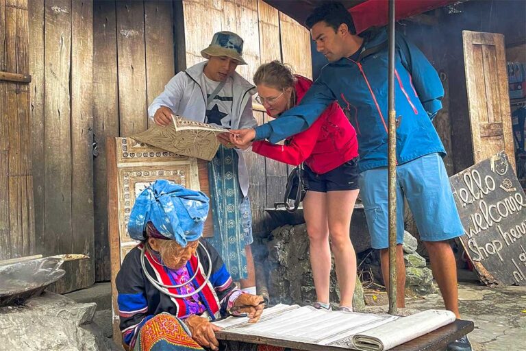 Visitors learning about traditional weaving techniques from a local artisan in Lung Tam village during a Ha Giang Loop cultural tour