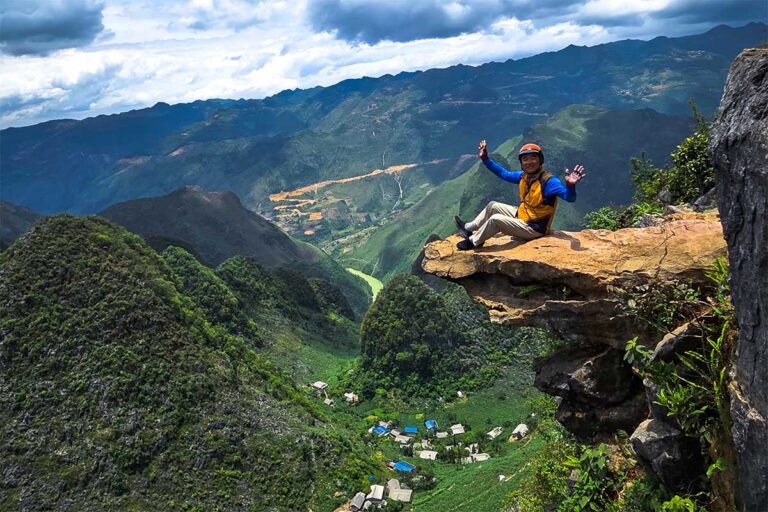 Traveler enjoying the Ma Pi Leng Sky Walk during a Ha Giang Loop tour, overlooking deep valleys and winding rivers