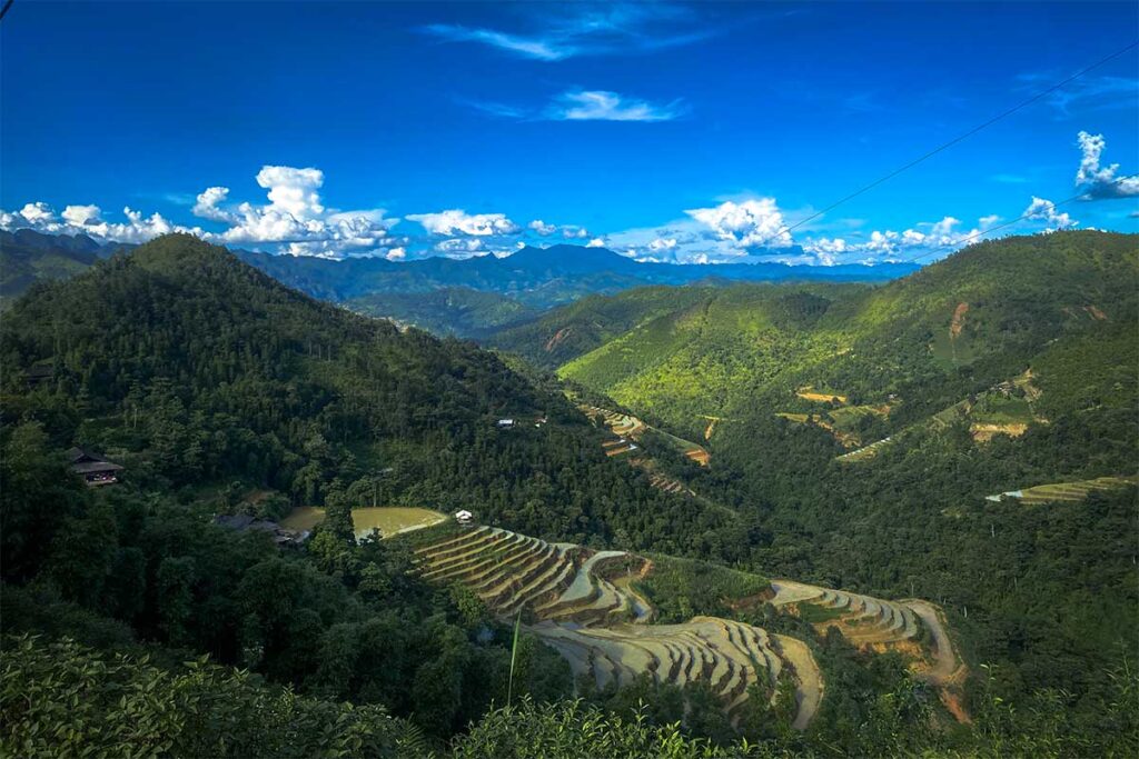 Wide valley view of Nham La terraced rice fields on the Ha Giang Loop, showcasing rural scenery and off-the-beaten-path routes by jeep or car