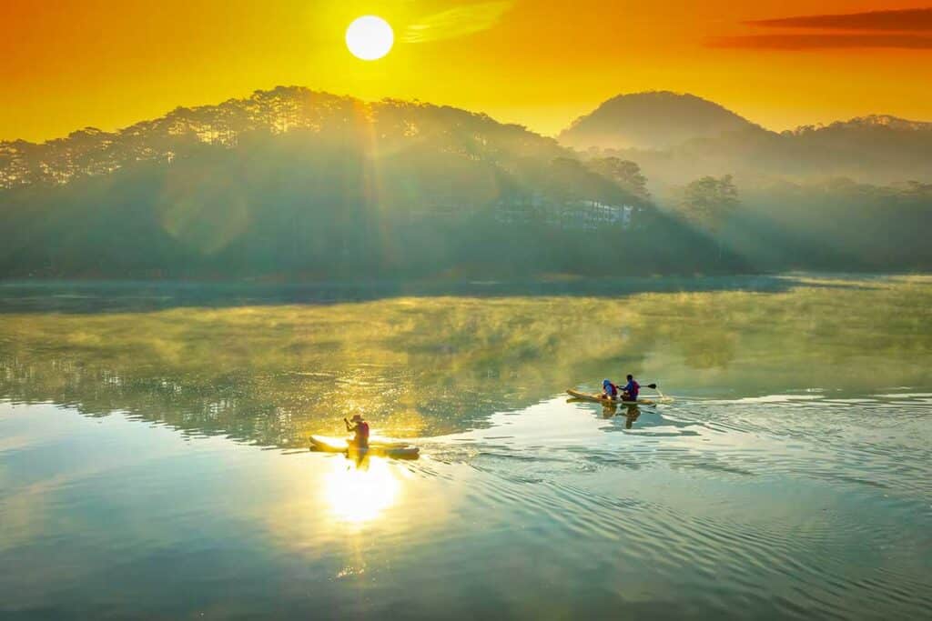 Stand up paddling on calm waters of Tuyen Lam Lake in Dalat, a popular outdoor activity on active Dalat tours