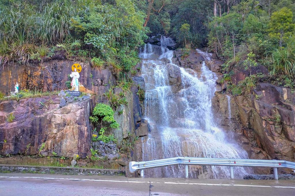 Small roadside waterfall flowing down rocky cliffs along Khanh Le Pass, a natural highlight on the Dalat to Nha Trang route