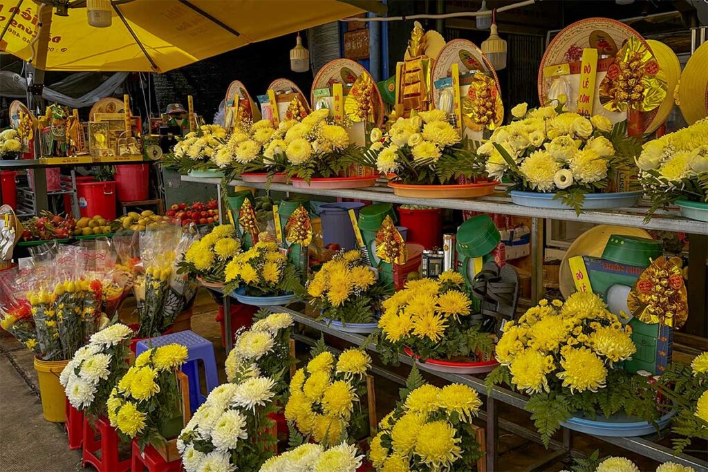 Flower and offering stalls at Con Dao Market with yellow chrysanthemums, incense and ceremonial items used for visits to Hang Duong Cemetery