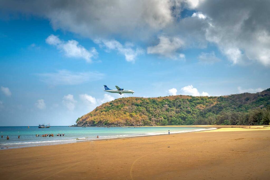 Passenger plane flying low over Dam Trau Beach in Con Dao just before landing, showing how to get to Con Dao by air with coastline and clear blue sea in the background