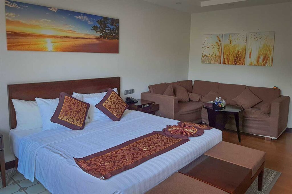 Simple hotel room at Con Dao Resort with large bed, seating area, and traditional interior design