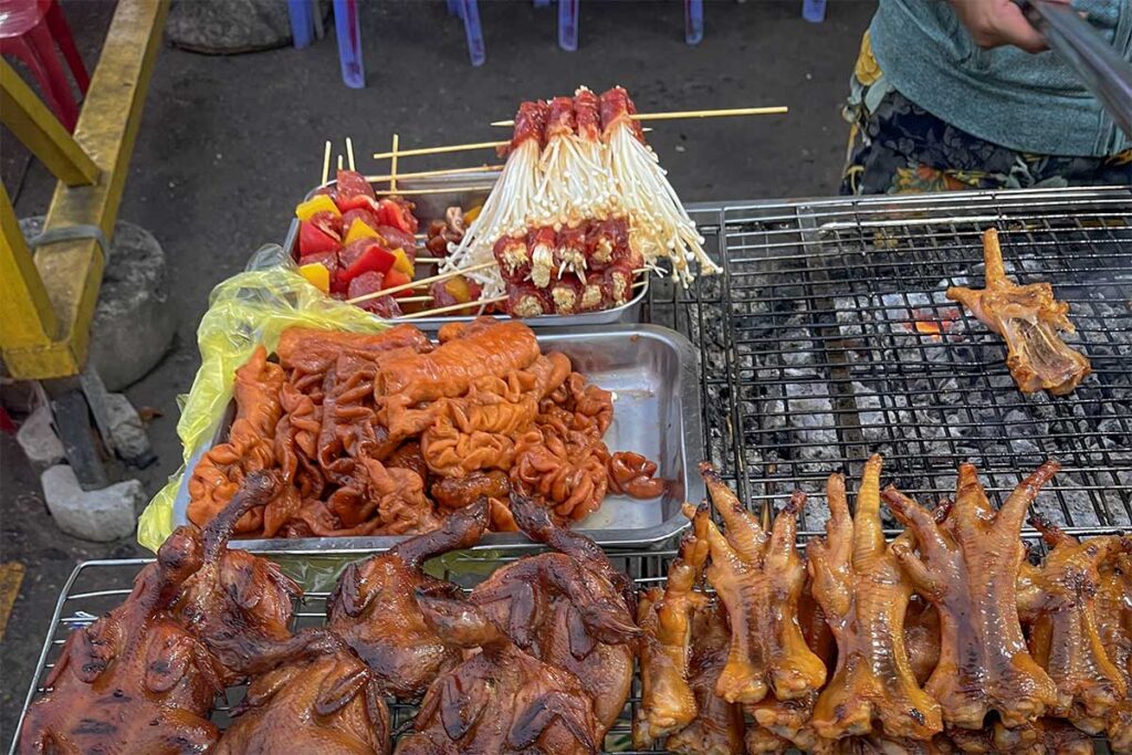 Grilled street food at Con Dao night market with skewers, chicken feet and local snacks cooking over charcoal in a casual outdoor setting
