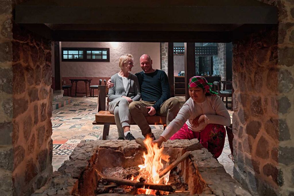 Guests and Hmong staff sitting around a traditional fireplace in the restaurant of Ha Giang Aya Lodge in northern Vietnam.