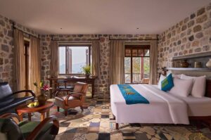 Spacious suite room at Ha Giang Aya Lodge with stone walls, seating area and mountain views of the Dong Van Karst Plateau in Ha Giang.