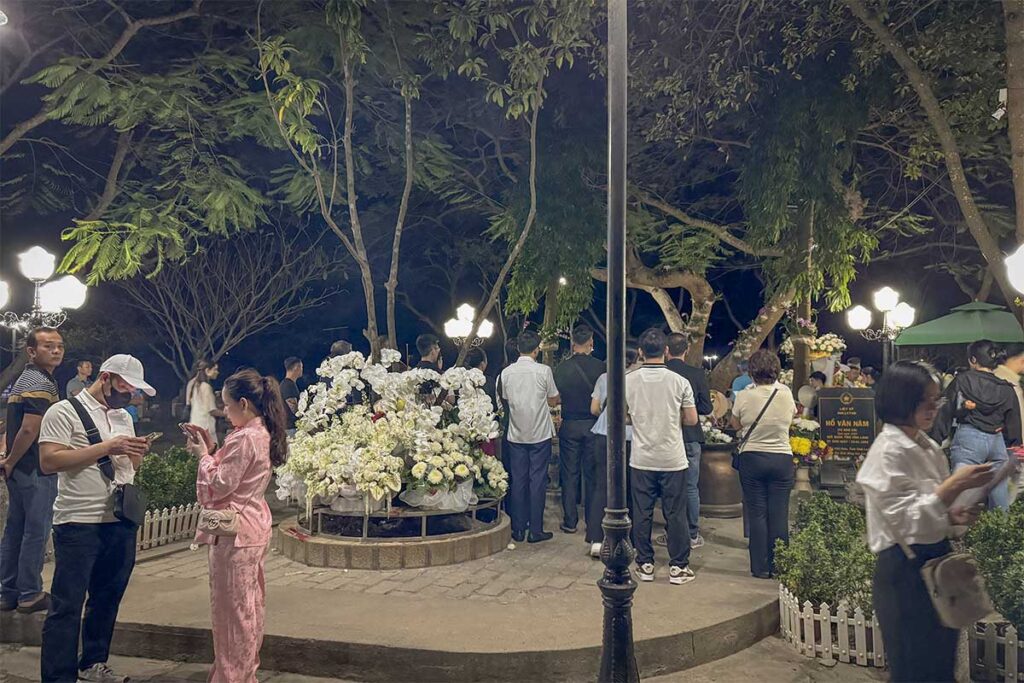 Visitors gathered around graves at Hang Duong Cemetery at night, with flowers and offerings creating a quiet and spiritual atmosphere on Con Dao.