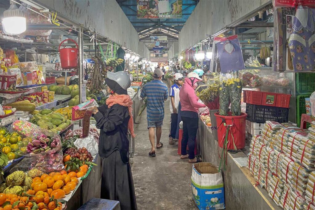 Locals walking through the indoor section of Con Dao Market with stalls selling fruits, vegetables, flowers and daily groceries