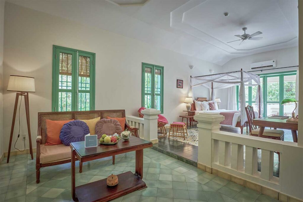 Spacious colonial-style villa interior at Poulo Condor Resort Con Dao with canopy bed, wooden furniture, and green shutters