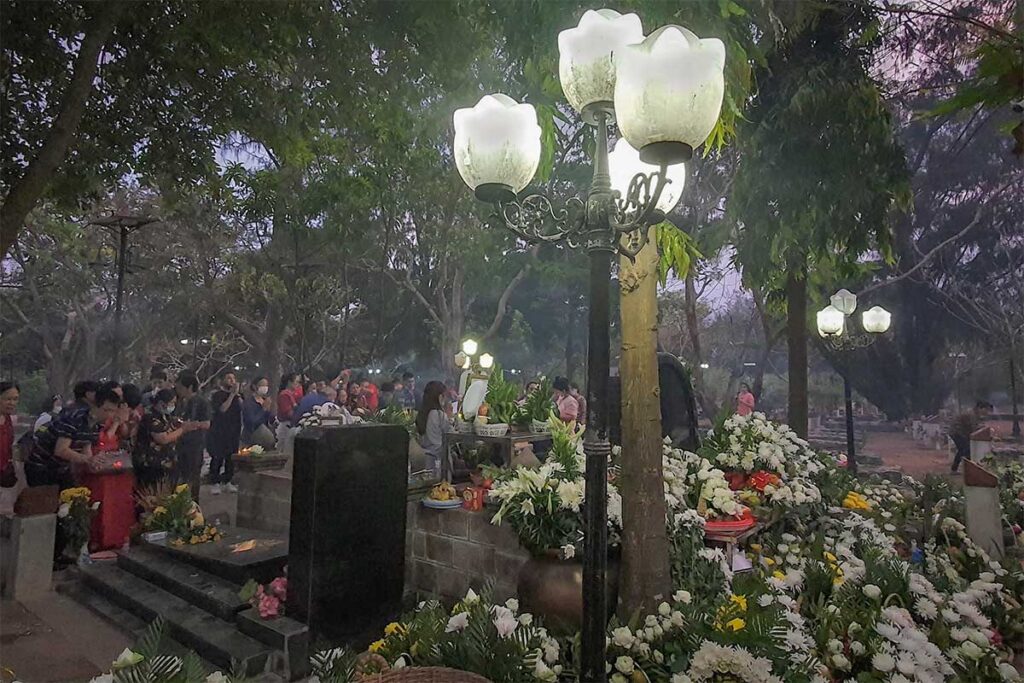Visitors gathered at Vo Thi Sau grave at night with flowers and offerings, creating a spiritual atmosphere at Hang Duong Cemetery in Con Dao.