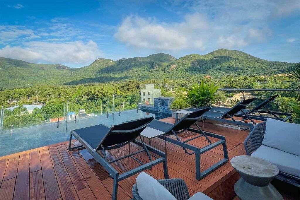 Rooftop pool at The Mystery Hotel Con Dao with sun loungers and panoramic views of green mountains and surrounding landscape