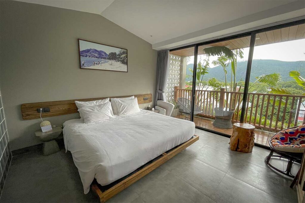 Modern hotel room at The Mystery Hotel Con Dao with balcony overlooking the town and nearby hills