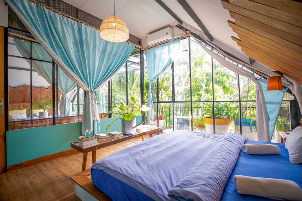 Bright and cozy room at Uyên’s House hostel in Con Dao with large windows, plants, and a relaxed homestay atmosphere