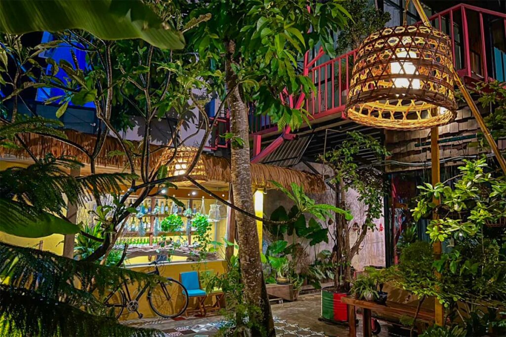 Garden courtyard at Uyên’s House hostel in Con Dao with tropical plants, warm lighting, and cozy communal area