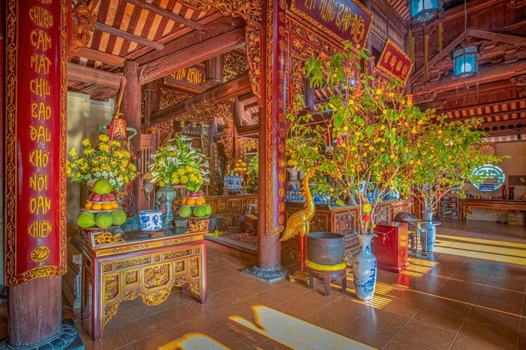 Interior of Van Son Pagoda showing wooden pillars, decorated altar and offerings inside the temple