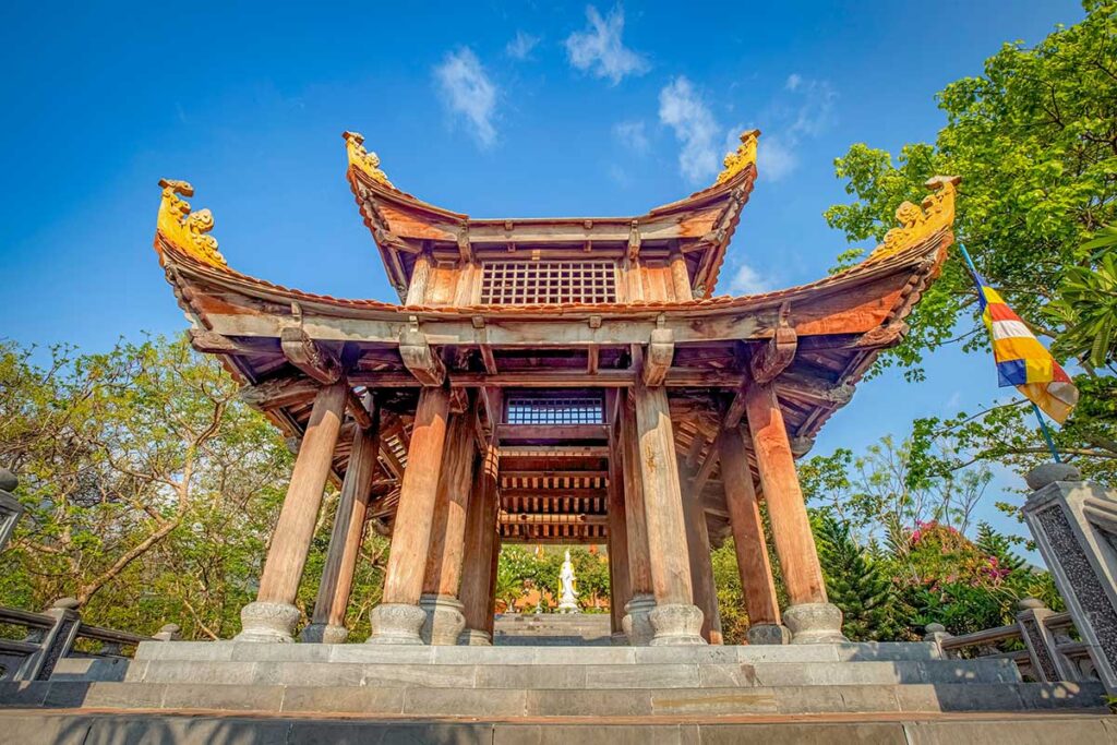 Traditional wooden gate and roof structure of Van Son Pagoda in Con Dao with blue sky background