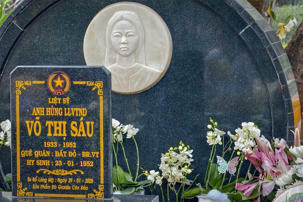 Close-up of Vo Thi Sau grave with flowers and offerings at Hang Duong Cemetery, one of the most visited spiritual sites on Con Dao.