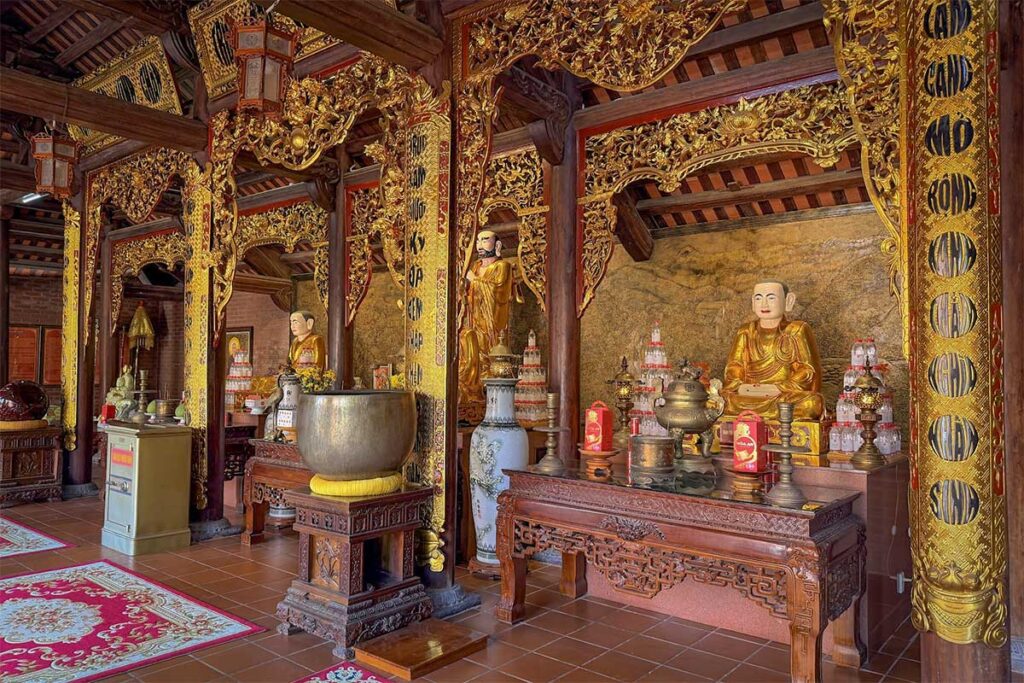 Interior altar of Ho Quoc Pagoda with golden statues wooden carvings and prayer space in Phu Quoc