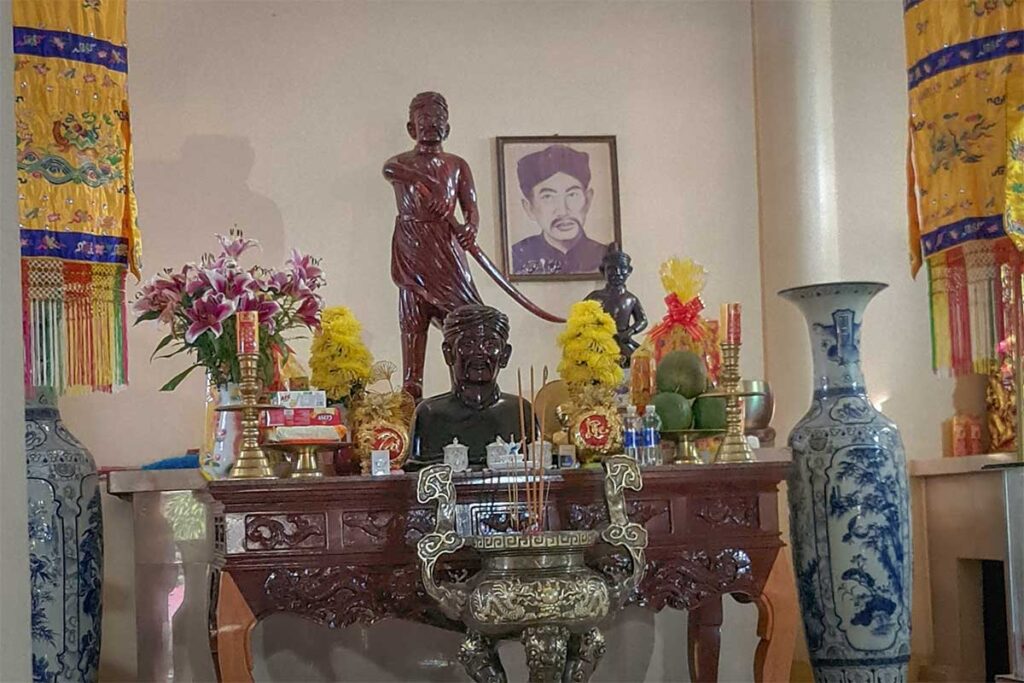 Altar inside Nguyen Trung Truc Temple Phu Quoc with offerings incense flowers and hero statue