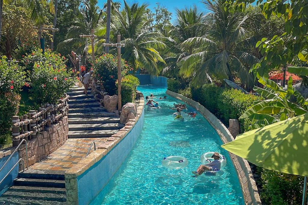 Aquatopia Water Park Phu Quoc lazy river with visitors floating on tubes through palm trees and tropical scenery