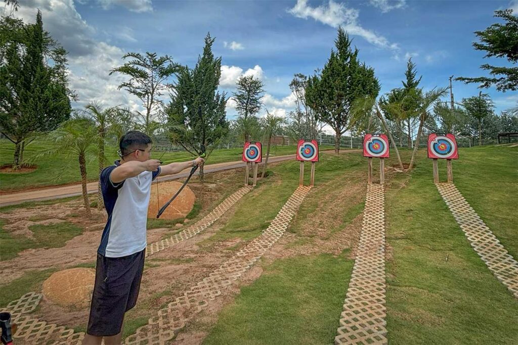Visitor trying archery at Mongo Land Dalat aiming at targets set up in an outdoor grassy area