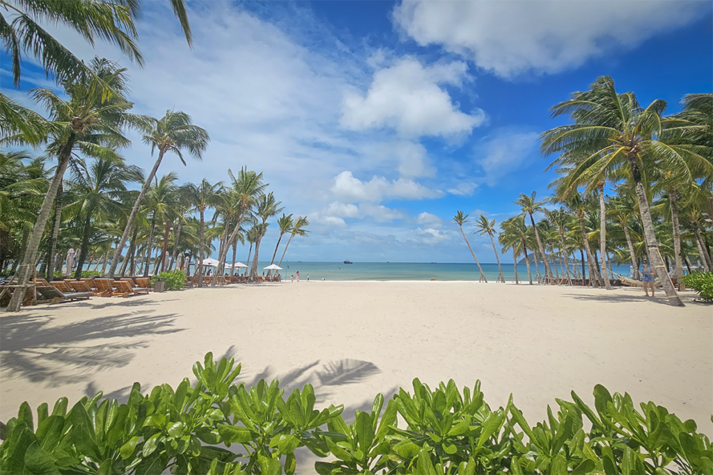 Wide view of Bai Khem Beach Phu Quoc with white sand tall palm trees and calm blue sea