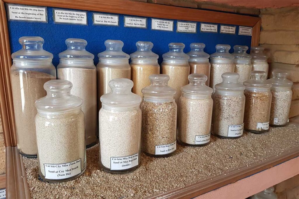 Glass jars filled with beach sand samples displayed inside Coi Nguon Museum Phu Quoc educational collection