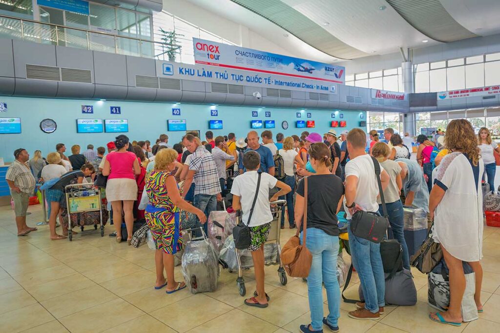 Crowded check-in area at Cam Ranh Airport with many travelers lining up at departure counters during busy hours