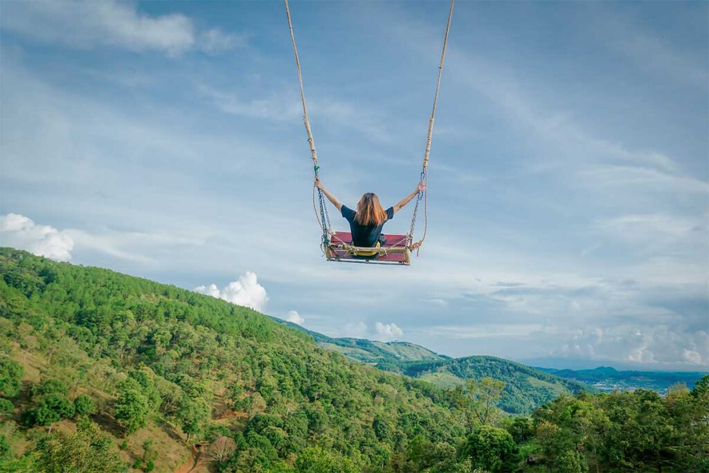 Visitor on a giant swing overlooking green mountains at Cao Nguyen Hoa, a popular photo and activity spot near the Mario Kart Dalat luge ride