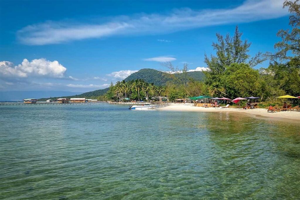 Scenic coastline of Starfish Beach Phu Quoc with white sand umbrellas and mountain backdrop