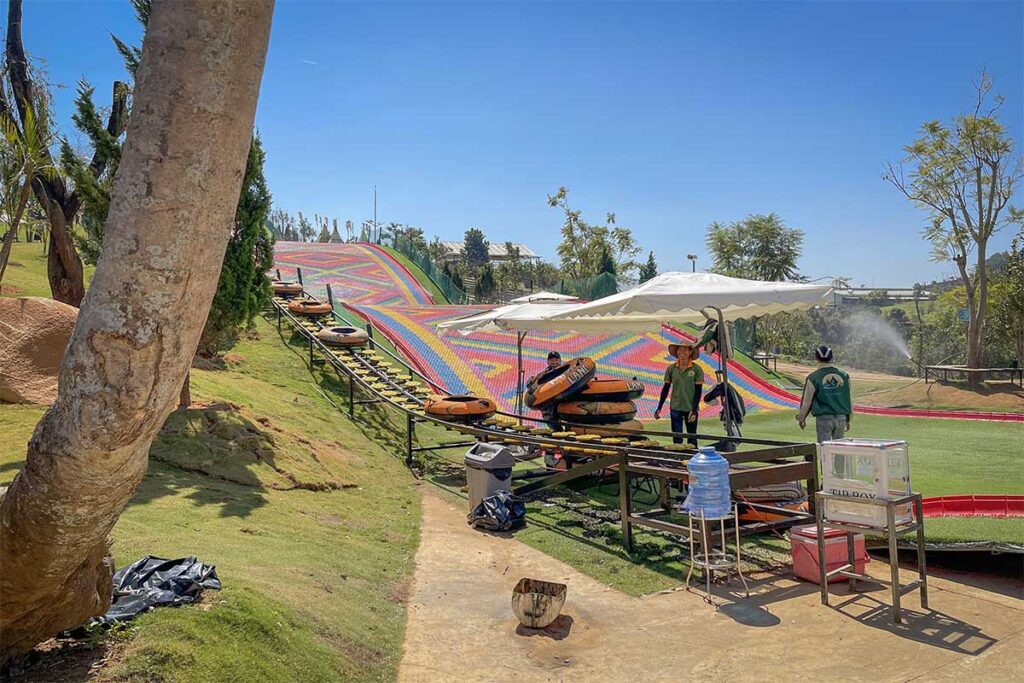 Colorful rainbow slide at Mongo Land Dalat with inflatable tubes being transported uphill on a conveyor system