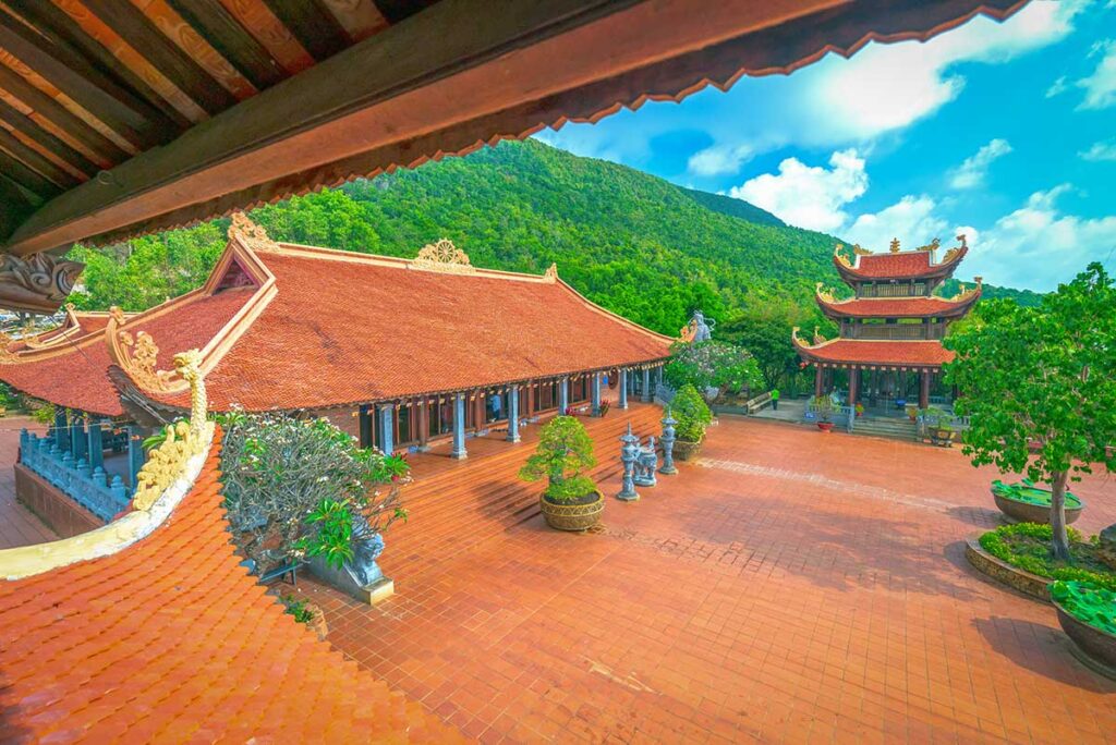 Courtyard and temple towers at Ho Quoc Pagoda with mountain backdrop in Phu Quoc
