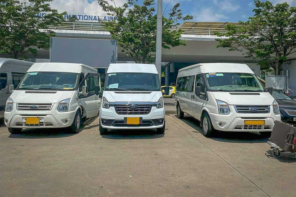 Shuttle vans waiting at Da Nang International Airport for transfers from Da Nang to Hoi An, a common option for shared transport between the airport and Hoi An hotels.
