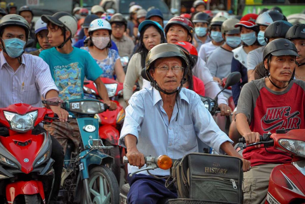 busy traffic in Vietnam with many motorbike riders wearing masks to protect against air pollution