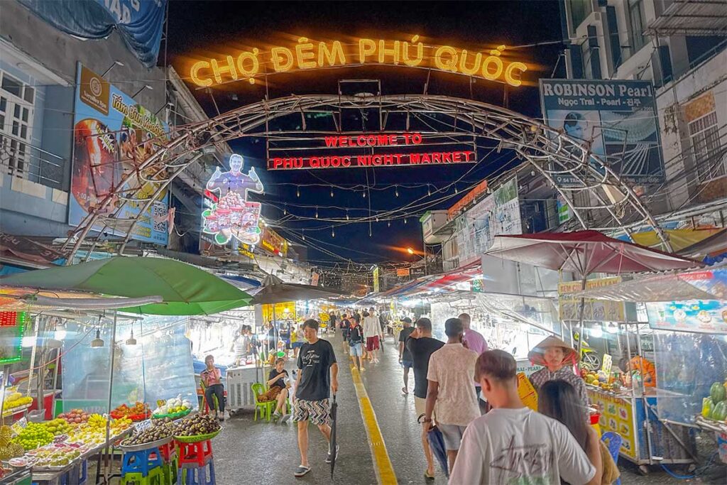 entrance sign of Phu Quoc Night Market in Duong Dong with visitors walking inside at night
