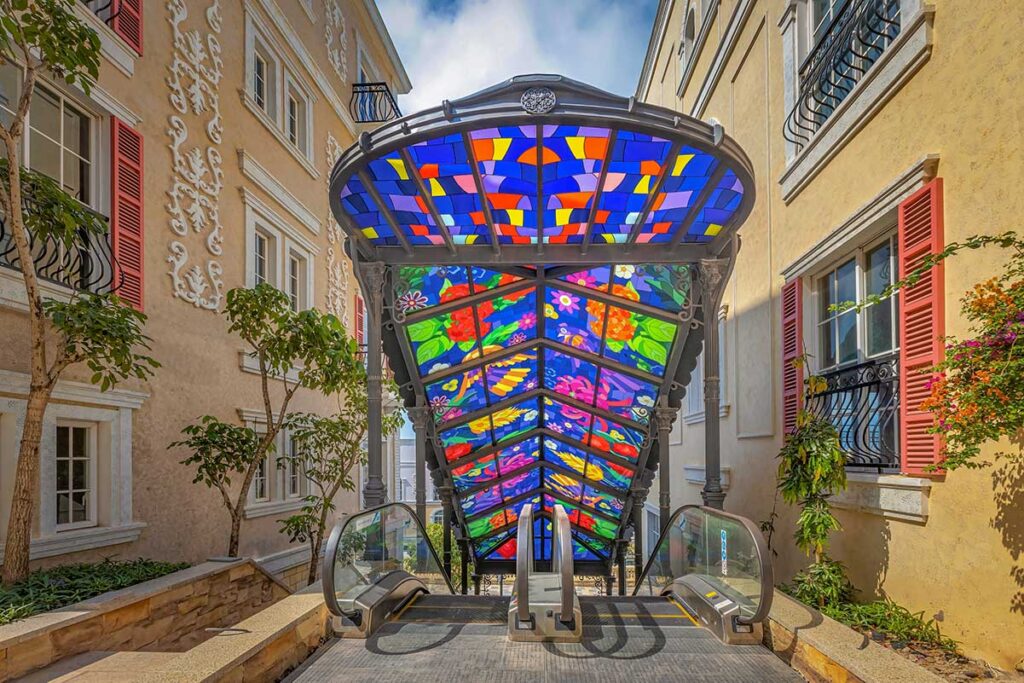 Colorful glass canopy above escalator in Sunset Town Phu Quoc with Mediterranean style buildings and decorative facades
