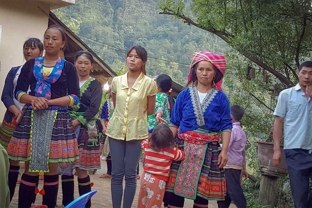 Hmong villagers in traditional clothing gathered in Sin Suoi Ho showing daily life in the village
