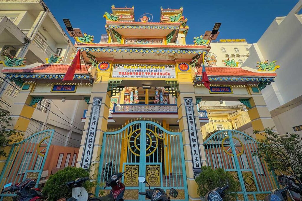 Front gate of Cao Dai Temple in Phu Quoc with ornate entrance colorful facade and parked motorbikes