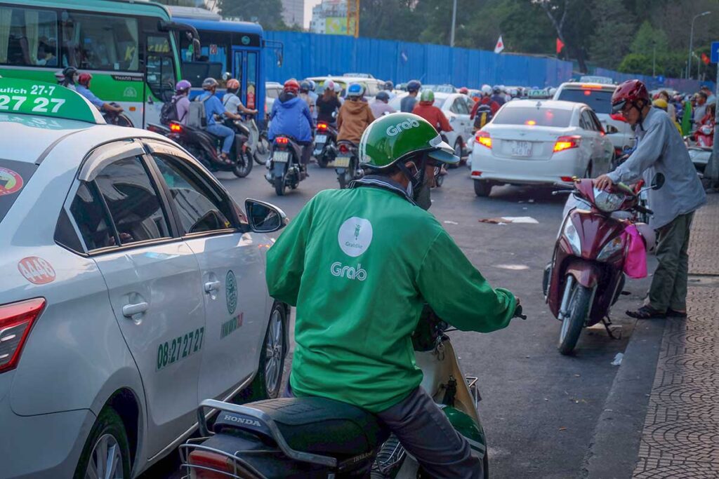 Grab motorbike taxi rider waiting in heavy traffic in Vietnam, a reliable transport option to avoid taxi scams